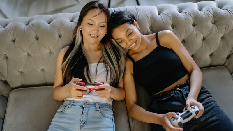 Dos mujeres que se relajan y juegan videojuegos en un cómodo sofá juntos.