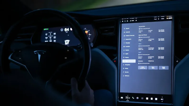 Vista interior de un automóvil eléctrico que muestra la pantalla táctil avanzada y el volante por la noche.