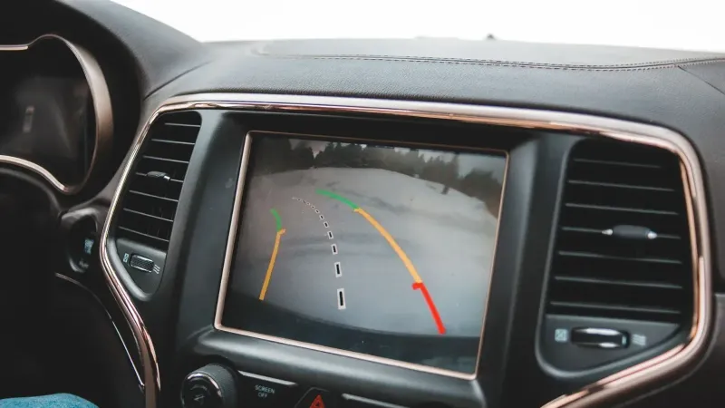 Primer plano del tablero de un automóvil que muestra una pantalla de cámara de retrovisor para la asistencia de estacionamiento.