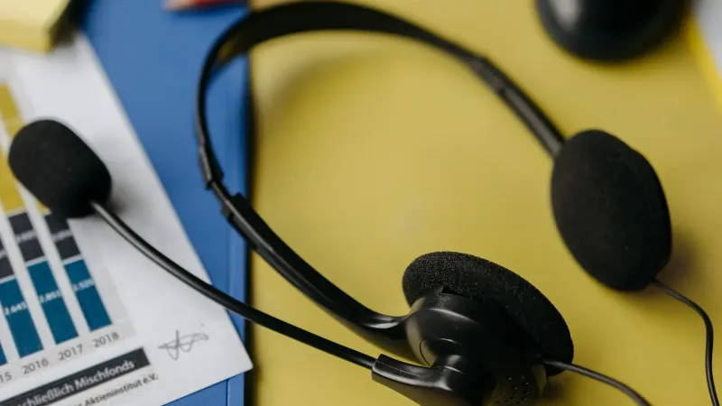Primer plano de un auricular en un escritorio con gráficos y suministros de oficina.