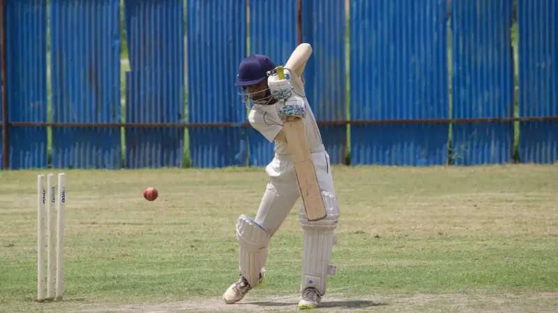 Jugador de críquet en acción, bateando en un campo de hierba en Gahunje, India.