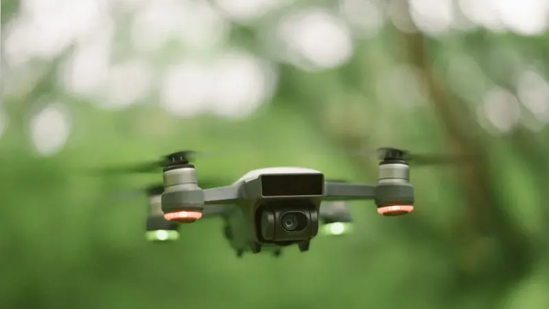 Un dron con luces rojas y verdes se cierne en un ambiente verde exuberante.