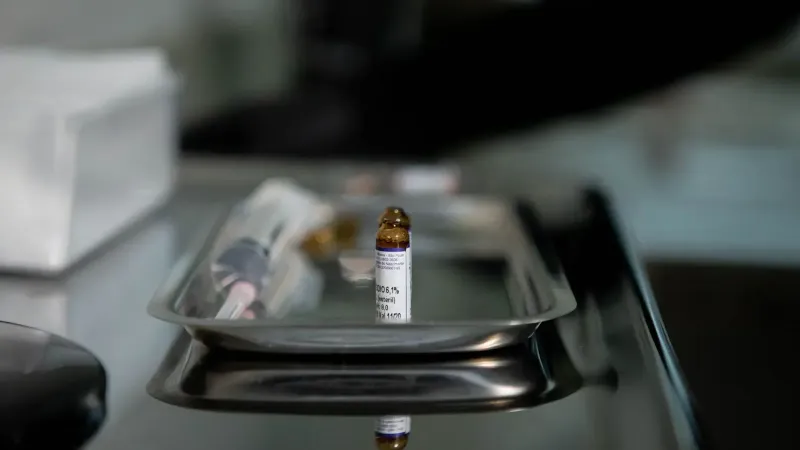 Focus on a vial placed on a stainless steel tray, reflecting a clinical and sterile medical environment.