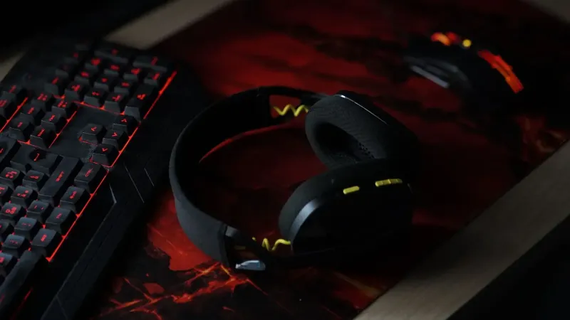 Una elegante configuración de juego con un teclado retroiluminado, auriculares inalámbricos y un mouse para juegos en una almohadilla de escritorio vibrante.