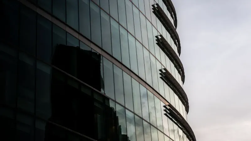 Contemporary glass office building reflecting cityscape in London, UK.