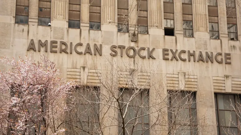 Facade of the American Stock Exchange Building in New York City during spring with blooming trees.