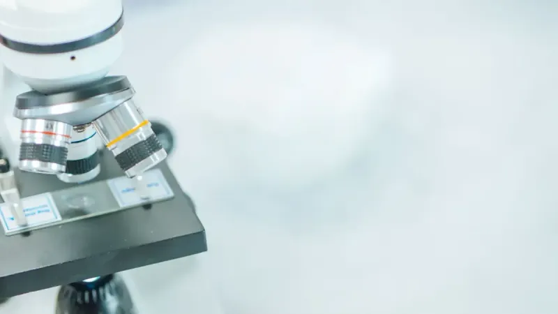 Primer plano detallado de un microscopio en un laboratorio con enfoque superficial resaltando sus componentes.