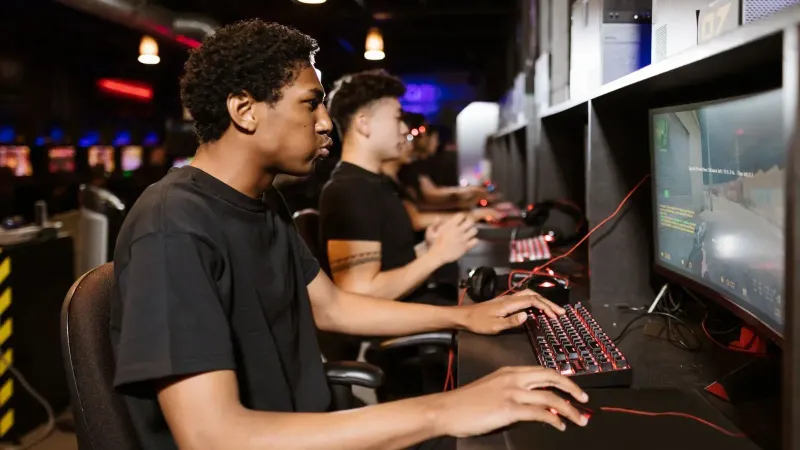 Group of young adults deeply engaged in competitive online gaming at a cyber cafe.
