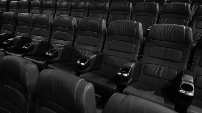 Imagen en blanco y negro de asientos de cuero vacíos en un cine interior.