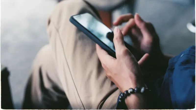Una vista de cerca de una persona que usa un teléfono inteligente en interiores, mostrando la tecnología moderna.