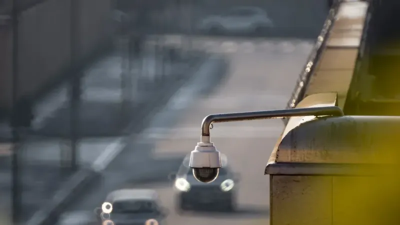 Cámara CCTV con vistas a una calle concurrida con coches en movimiento, capturando la vigilancia urbana.