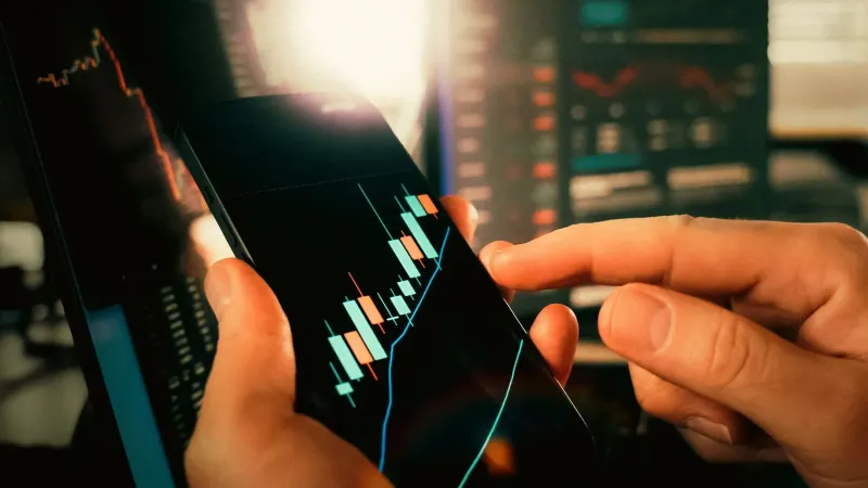 Manos interactuando con gráficos financieros en un teléfono inteligente, mostrando las tendencias del mercado de valores.