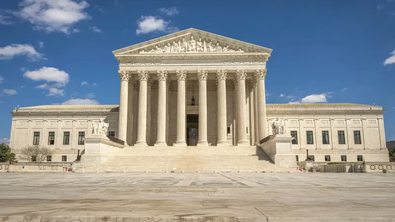The majestic facade of the United States Supreme Court under a clear blue sky.
