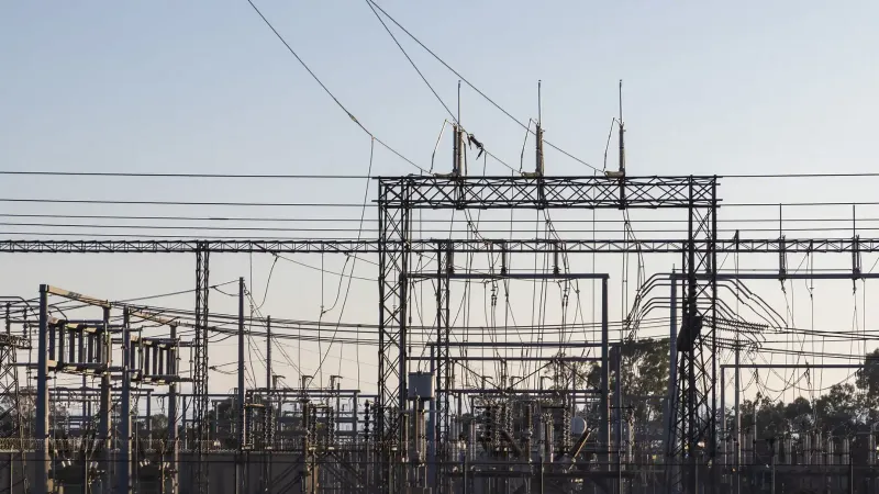 High-voltage electrical substation with steel structures and power lines at dawn.