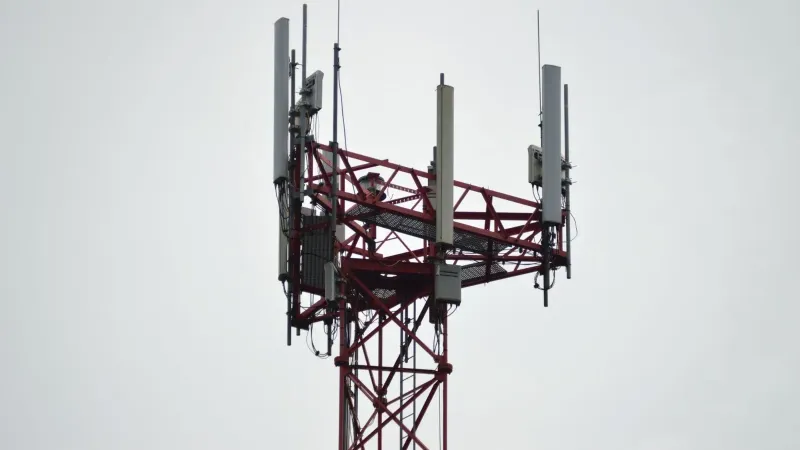 A red communication tower with antennas stands tall against a gray sky.