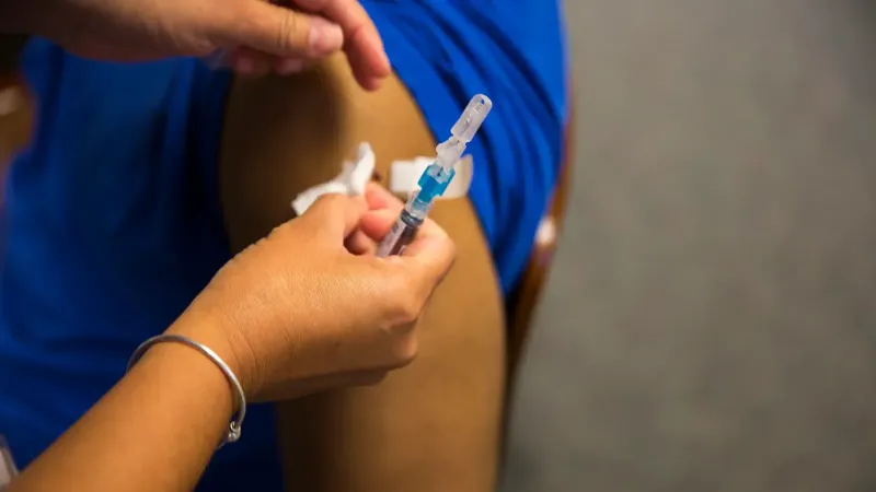 Un profesional de la salud pone una curita sobre el sitio de una inyección después de proporcionar una vacuna contra la gripe a un paciente durante un evento de vacunación contra la gripe