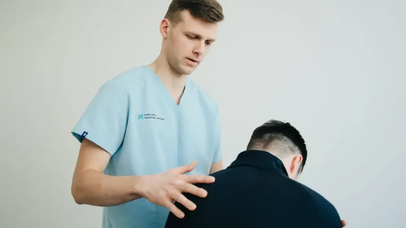 A physiotherapist assessing a patient's posture indoors, showing support and expertise.