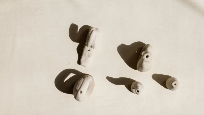 Artistic shot of handmade clay ocarinas on light background, highlighting shadows.