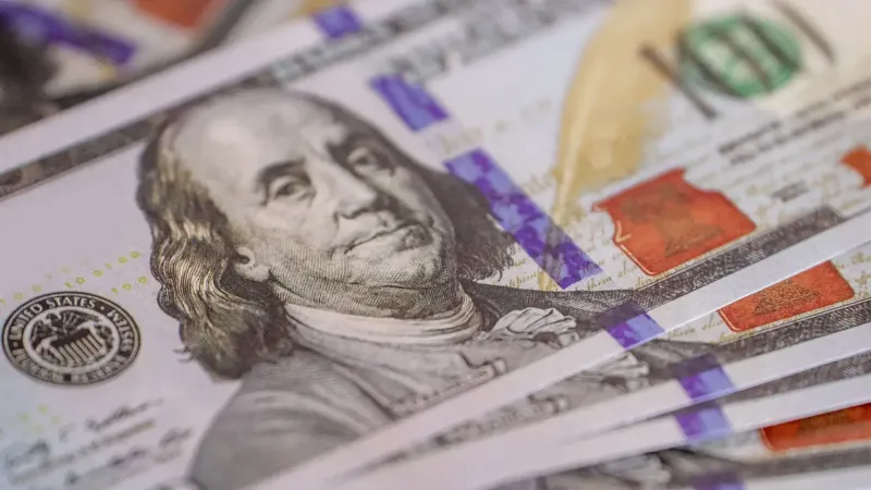 Imagen detallada de primer plano de billetes de cien dólares estadounidenses avivados, mostrando detalle de moneda.