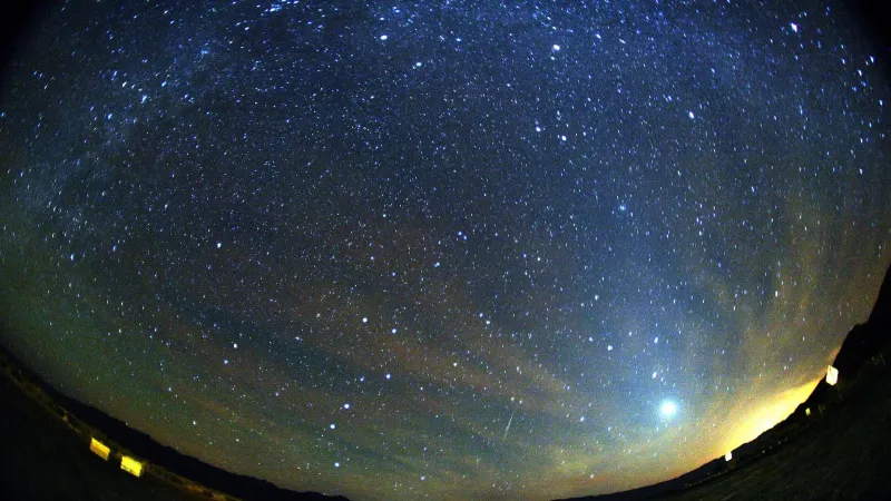 Un meteorito orionido verde y rojo golpeando el cielo debajo de la Vía Láctea ya la derecha de Venus.