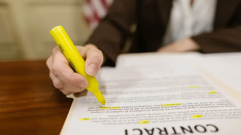 Un primer plano de una mano que destaca un contrato, enfatizando importantes términos legales.