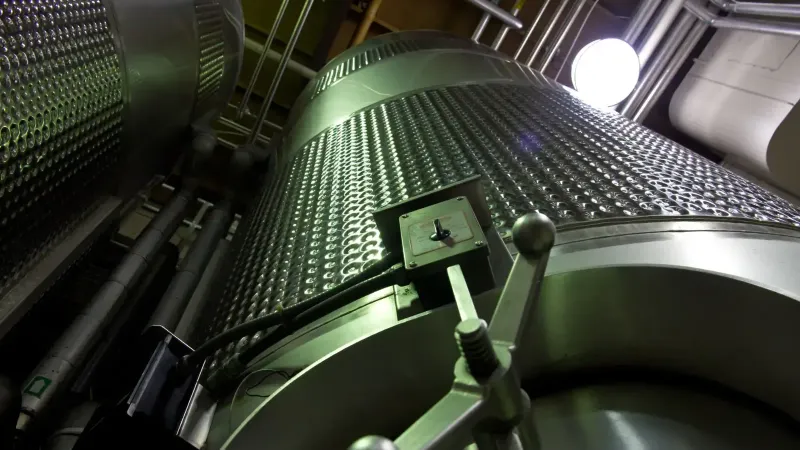 Low-angle shot of large stainless steel tanks inside a modern industrial facility.