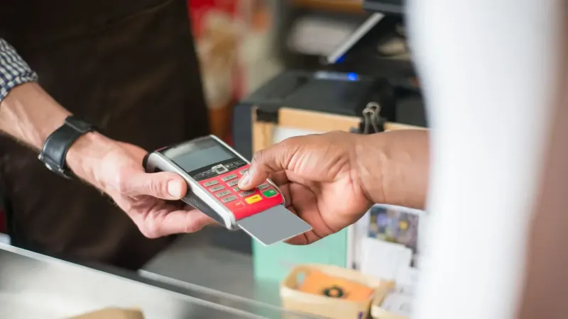 Un cliente usa una tarjeta para un pago sin contacto en una tienda minorista. Concepto de negocio y consumismo.