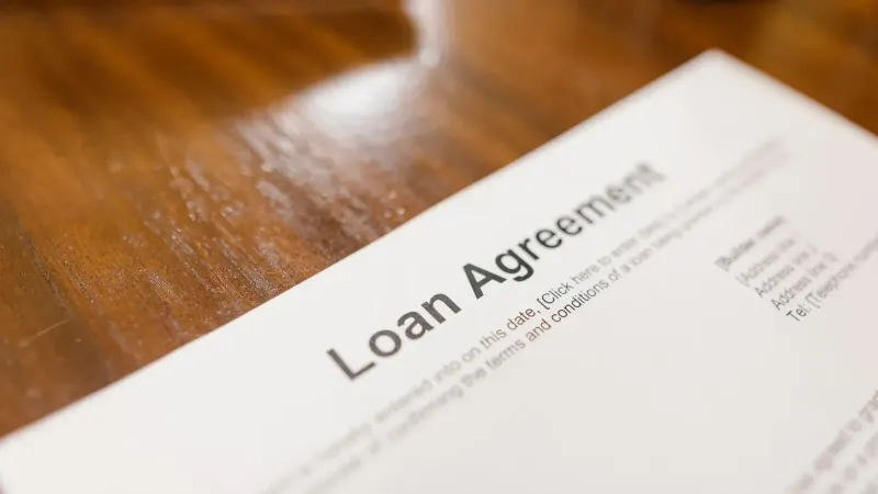 Detailed loan agreement document close-up on a wooden table representing legal and financial concepts.
