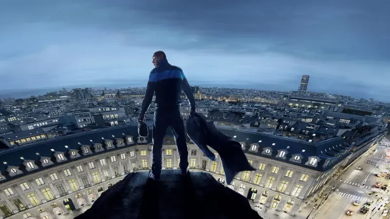 Omar Sy as Assane Diop stands on a tower above the streets of Paris in Season 3 of 'Lupin.'