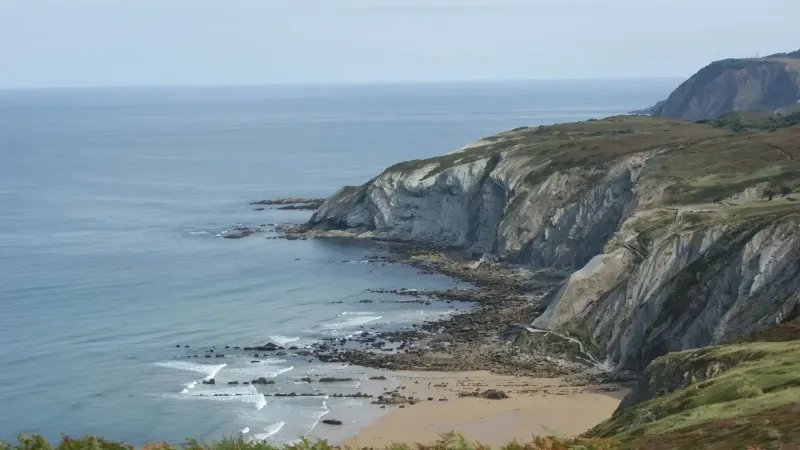 Majestuosos acantilados y tranquila playa a lo largo de una serena orilla del océano, ideal para los amantes de la naturaleza.