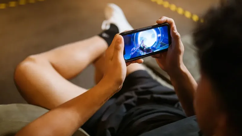 Man playing a video game on a smartphone while sitting comfortably indoors.