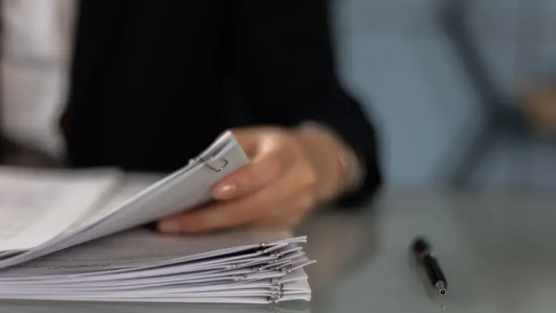 Close-up of a professional organizing a stack of documents on a desk.