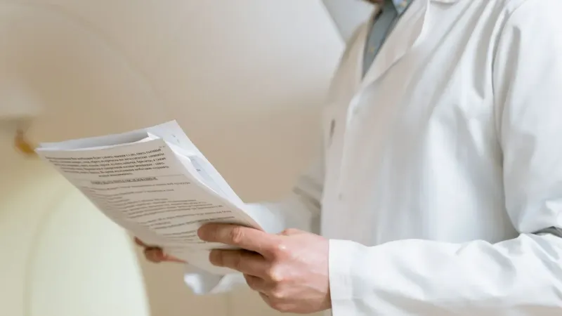 Doctor in a white coat examining medical papers in a healthcare setting.