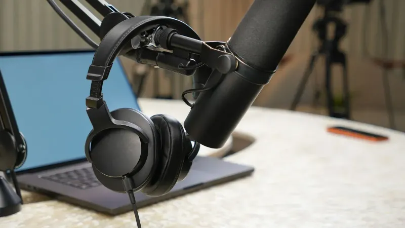 Primer plano de una configuración de estudio de podcast con un micrófono y auriculares.