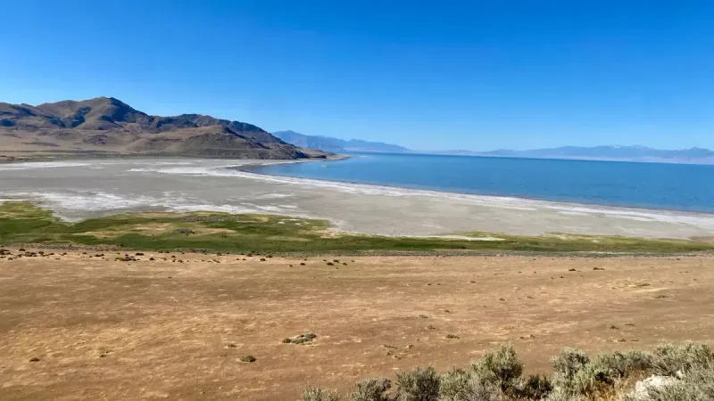 Paisaje sereno del Gran Lago Salado con montañas circundantes y cielos azules despejados.