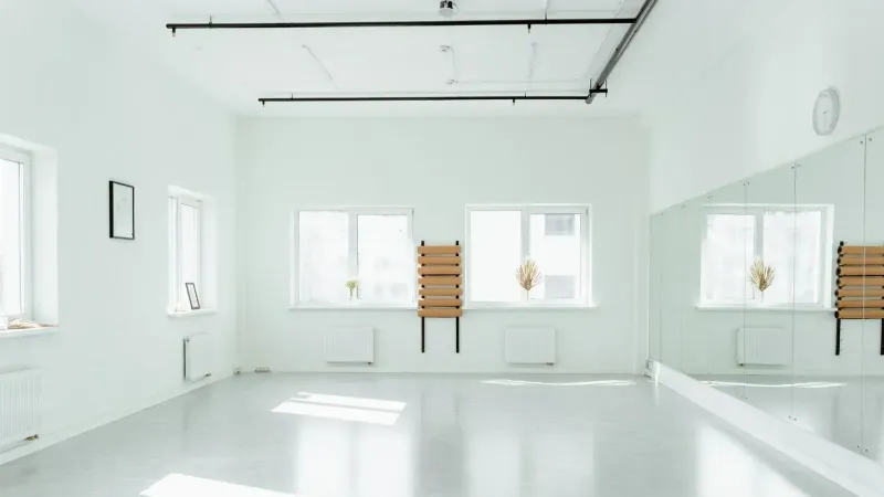 Estudio de baile brillante y vacío con espejos y luz solar en streaming.