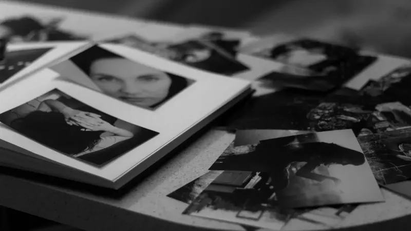 Una colección de fotos en blanco y negro esparcidas sobre una mesa, con retratos y composiciones artísticas.
