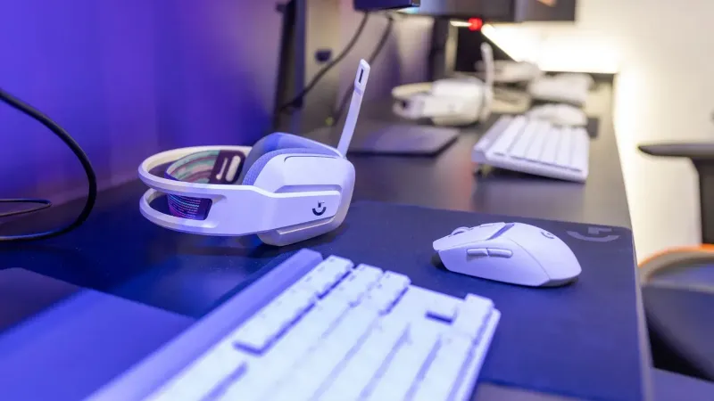 Close-up of a gaming setup featuring a white headset, computer mouse, and keyboard with a vivid lighting ambiance.