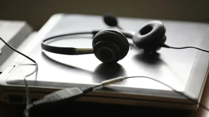 Auriculares negros acostados en una computadora portátil cerrada, simbolizando trabajo remoto o comunicación digital.