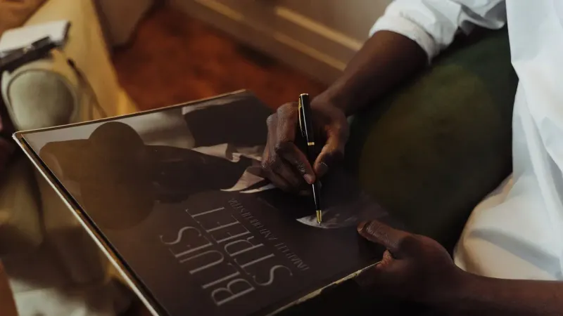 An individual signing a vintage vinyl record with a pen while sitting indoors.