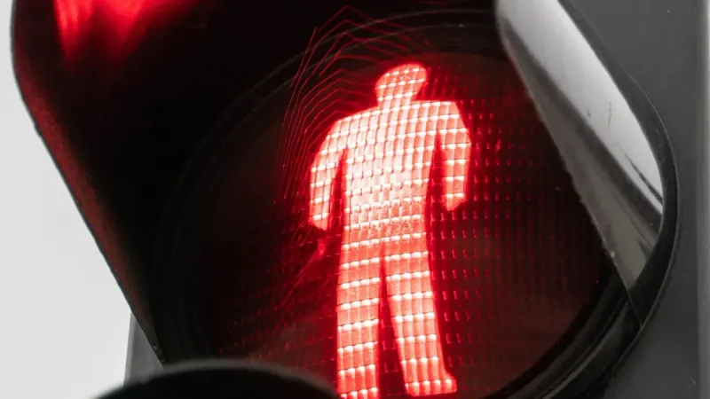 Vista detallada de una señal de cruce peatonal rojo que indica la parada.