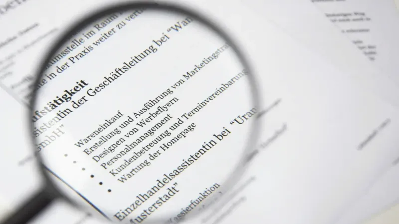 Primer plano de un texto de documento de negocios bajo una lupa.