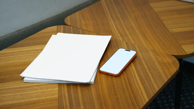 Un escritorio de oficina ordenado con un teléfono inteligente y una pila de papeles, ideal para entornos de negocios.