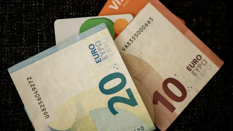 Close-up de billetes en euros y tarjetas de crédito en una superficie de textura oscura.