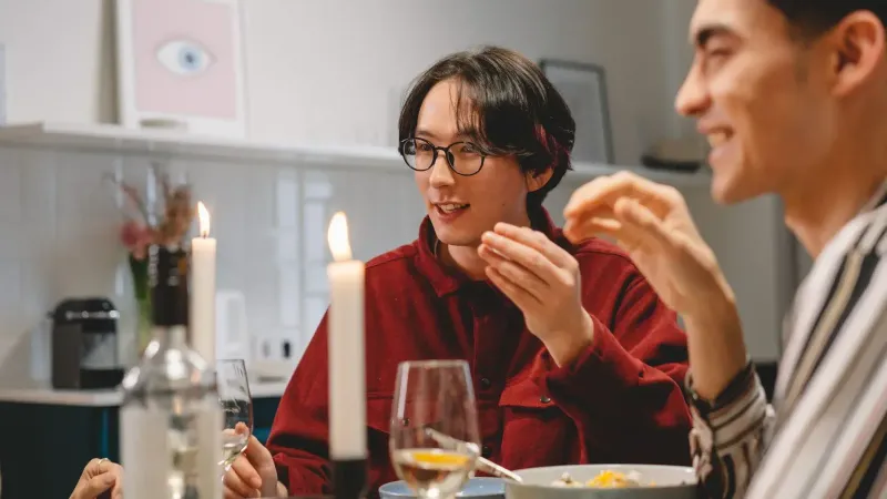 Una cena amistosa con amigos diversos disfrutando de la comida y la conversación en el interior.