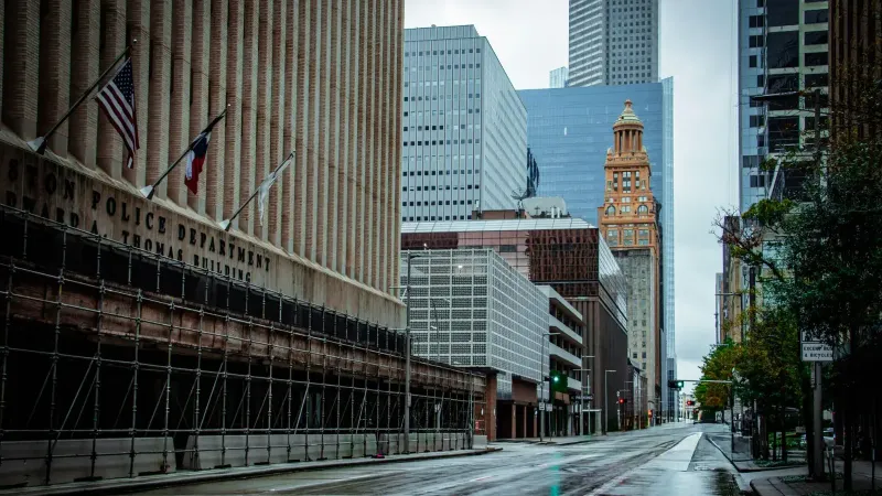 Una vista de día lluvioso de la arquitectura céntrica de Houston con edificios modernos e históricos, calle vacía.