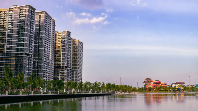 Una vista panorámica de los rascacielos urbanos junto a un tranquilo lago al atardecer.