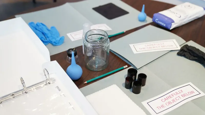 Herramientas forenses organizadas que incluyen guantes y frascos en una mesa para la investigación.