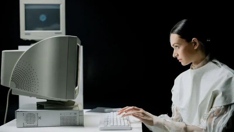 Una mujer escribiendo en una computadora CRT retro en un moderno laboratorio.