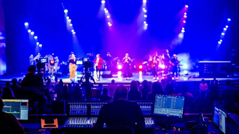 Ingeniero de sonido en un vibrante concierto en vivo con luces de escenario brillantes y audiencia.
